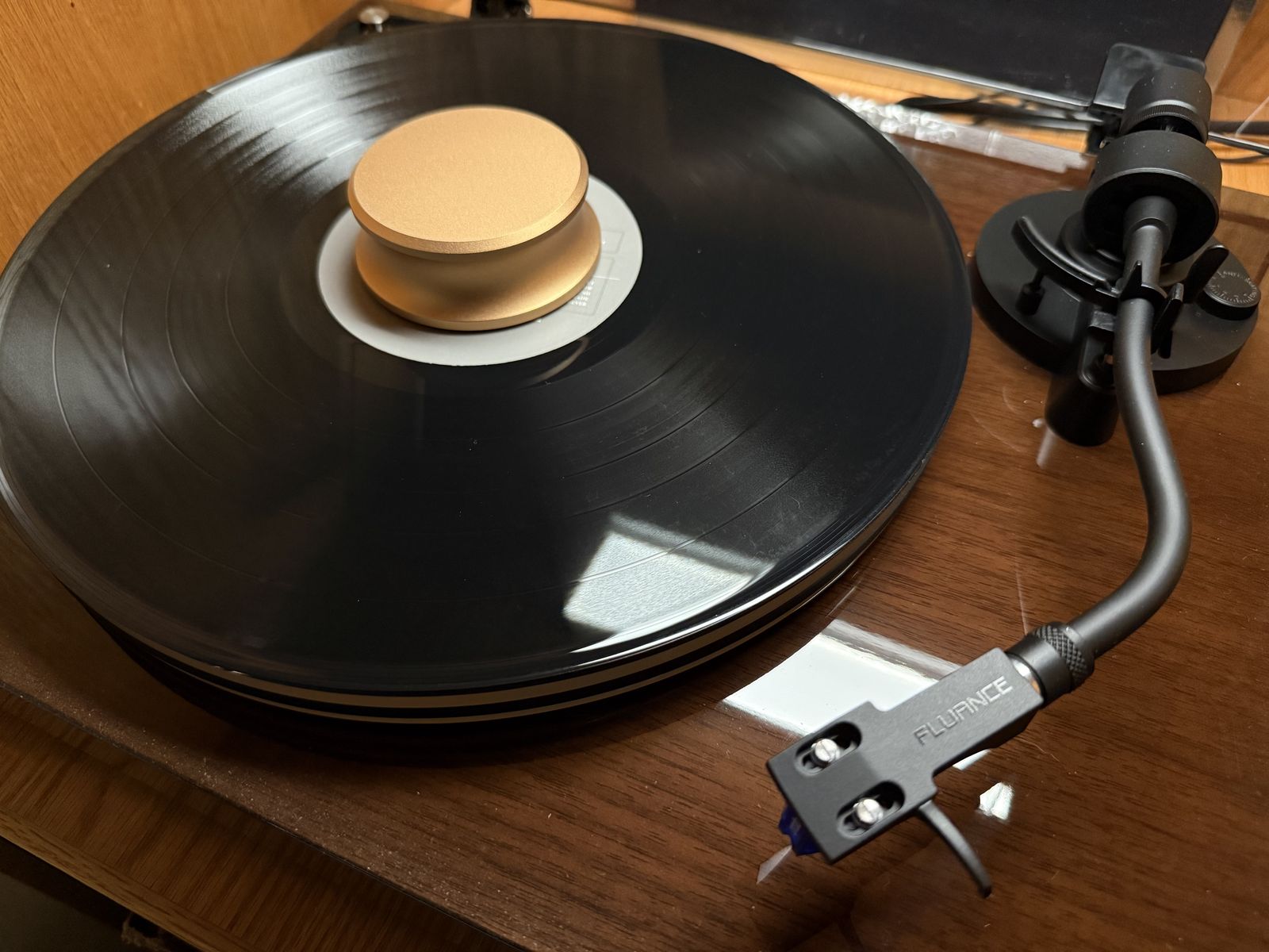 A record on a Fluance RT85 turntable with a gold record weight, ready to play