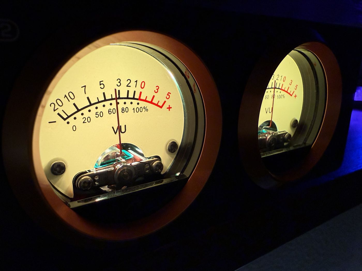 Two backlit analog VU meters glowing warm amber